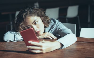 Sad young woman on smartphone