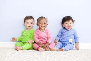 三个穿着绿色，粉色和蓝色衣服的宝宝。
