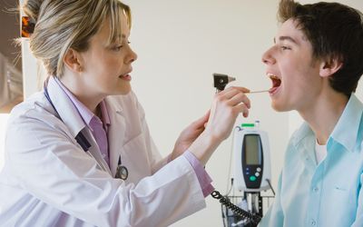 女医生正在检查少年病人的喉咙
