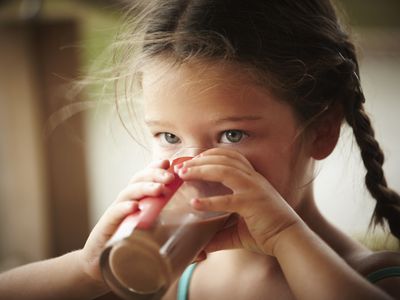 Close up of girl with braids drinking chocolate milk