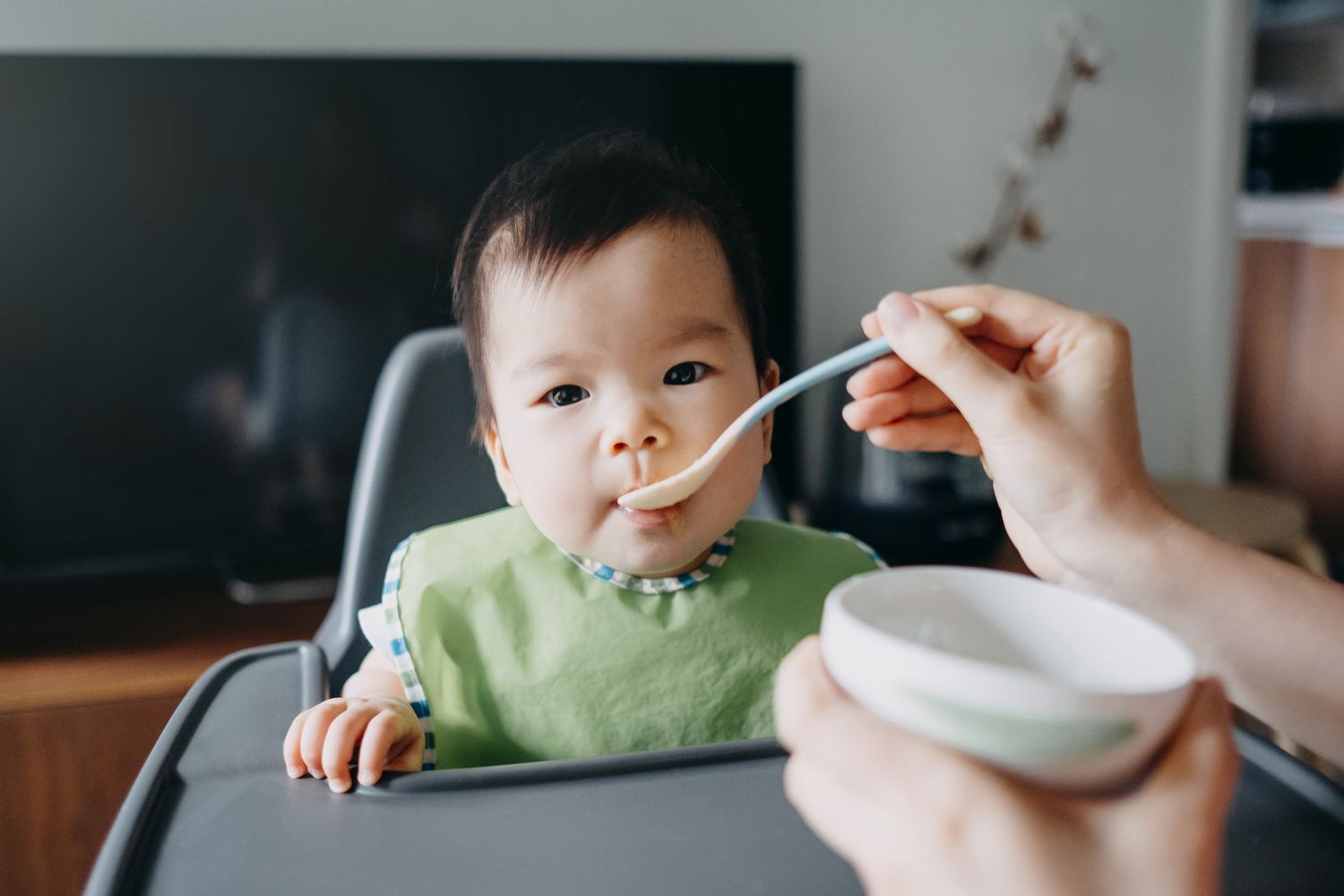 婴儿坐在高脚椅上被喂食
