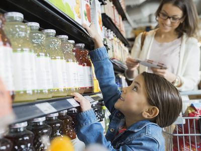 Girl reaching for juice on shelf in market