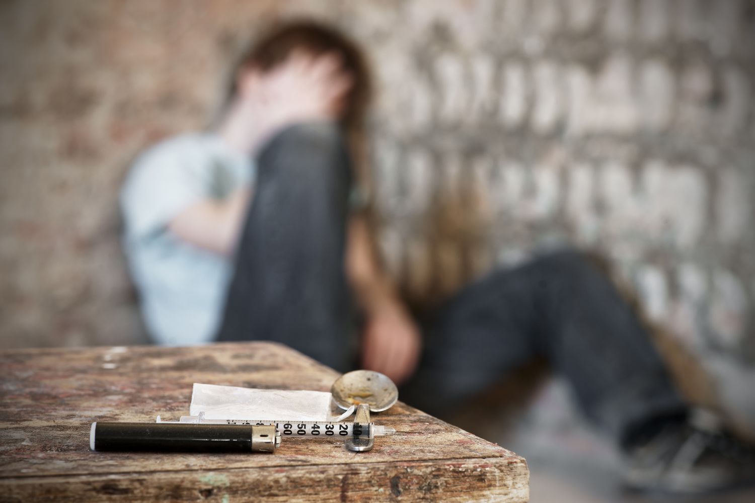 Drug paraphernalia with blurred teen sitting in background