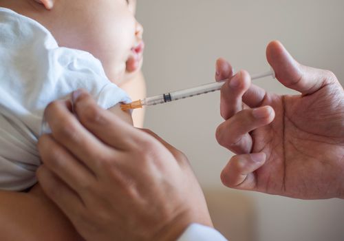 A doctor is injecting a vaccine to a baby boy