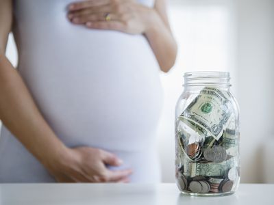 孕妇靠近一罐现金，代表省钱与迷你试管婴儿周期