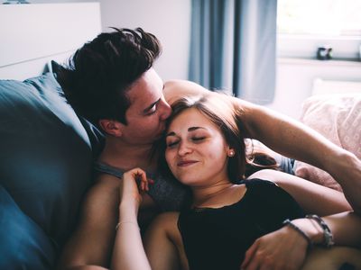 Couple in bed, man is kissing woman's head