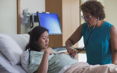 Doctor listening to belly of pregnant patient