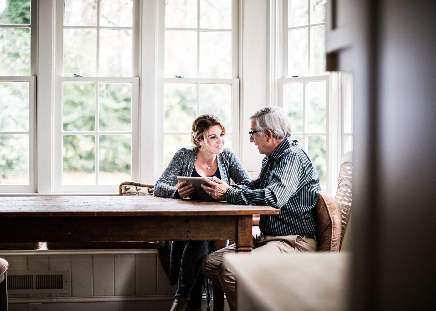 Adult woman and senior man talking at a kitchen table