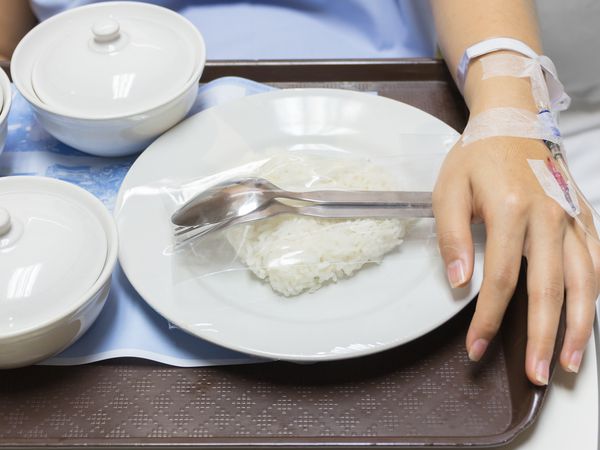 孕妇在白色的碗里滴注生理盐水和煮好的米饭和其他食物。