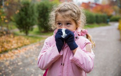 Little girl blowing her nose into a tissue