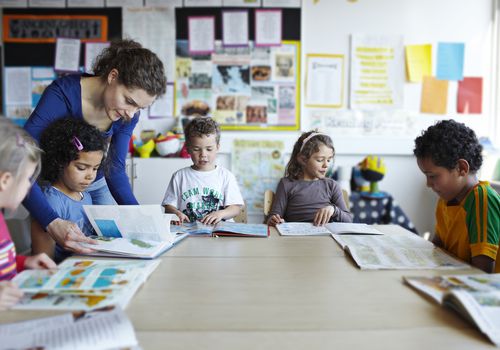 Teacher looking at books with young children