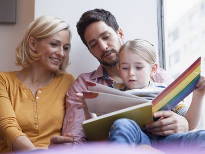 Parents reading a picture book with their daughter.