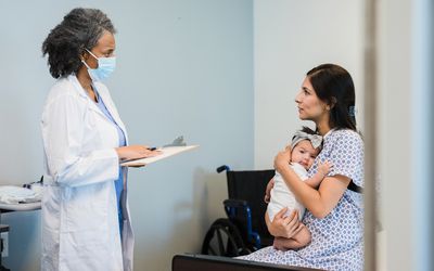 A physician talks to a woman holding a baby