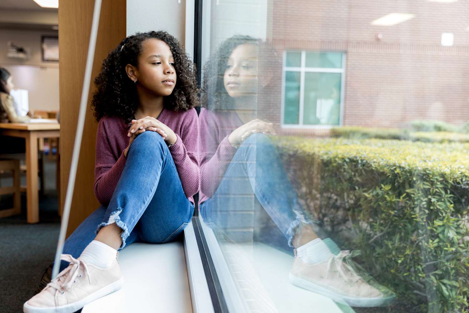 Young girl sitting on window ledge