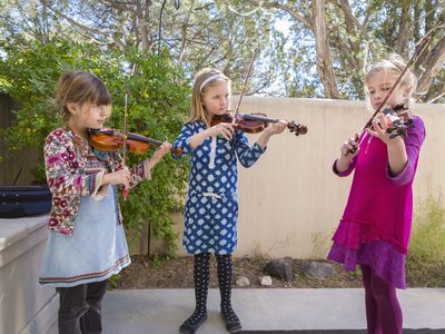 Three girls playing violin outside
