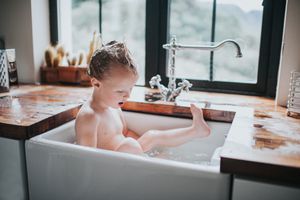 小男孩在厨房水槽里洗澡＂width=
