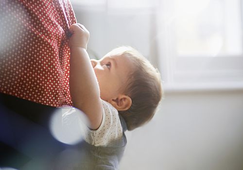toddler hanging on to mother's dress