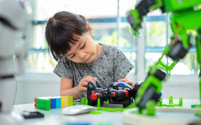Child builds and analyzing robotic parts while working in school