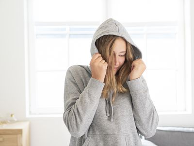 young teen hiding face in hoodie