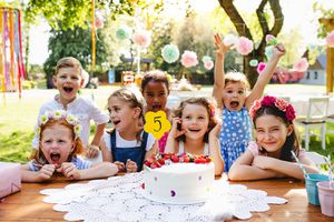 夏天，在花园的生日聚会上，孩子们拿着蛋糕围着桌子站着