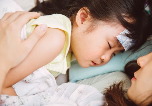 生病的小女孩和妈妈依偎在一起