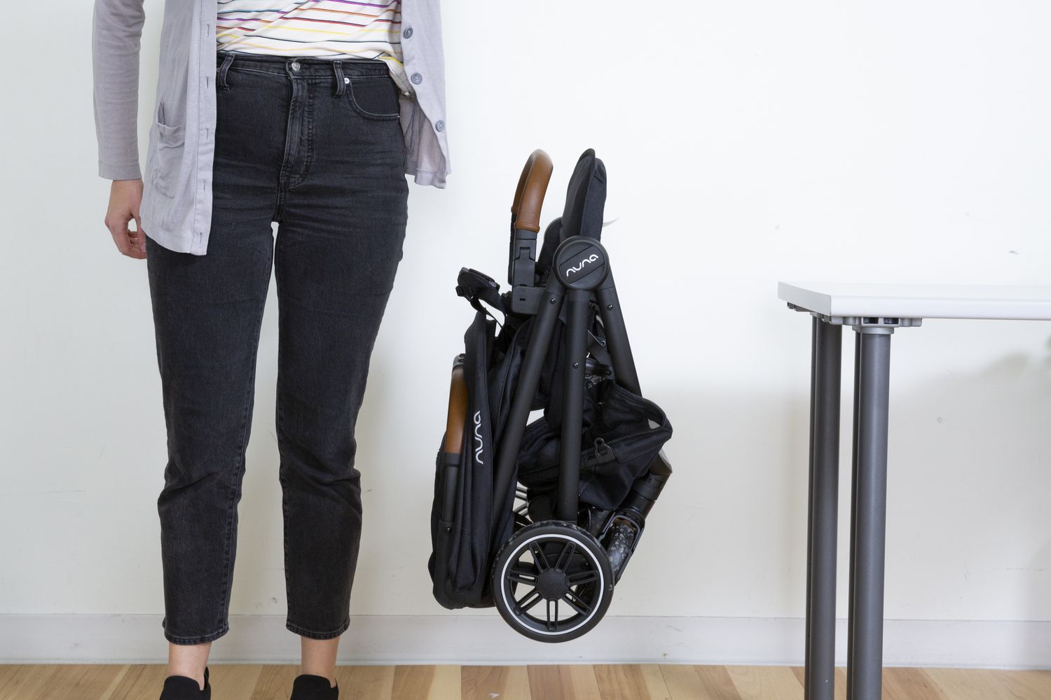 Person droping the folded Nuna TRVL Stroller