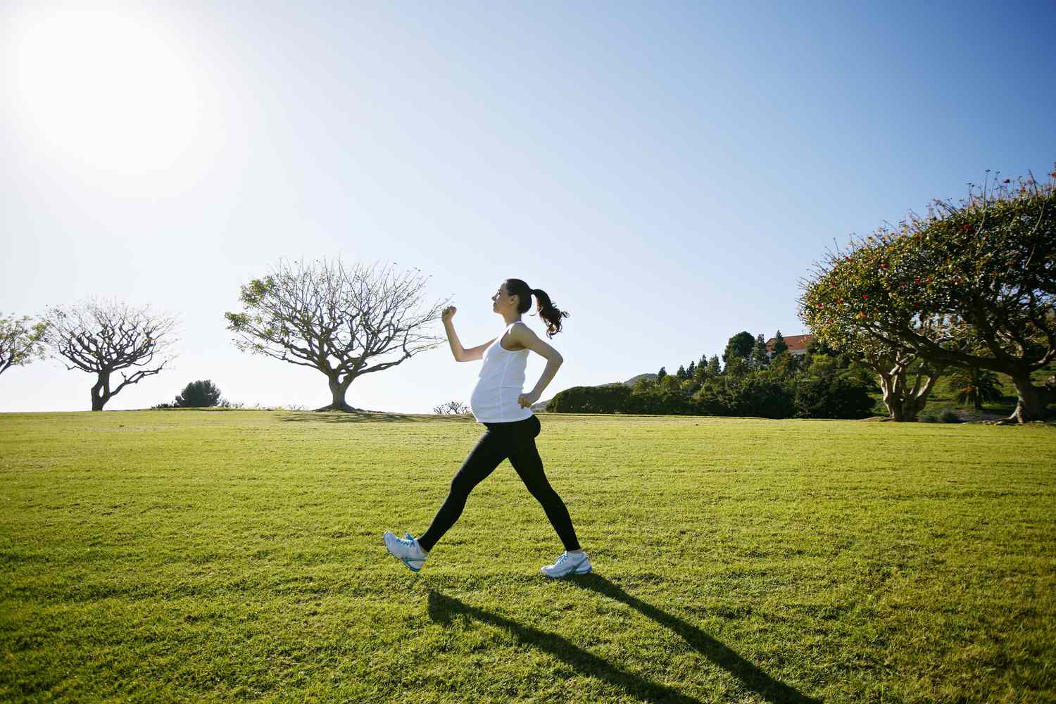 A pregnant person walks across a grassy field