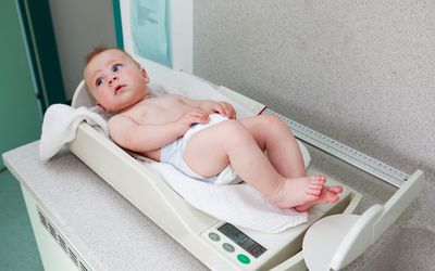 Baby girl at pediatrician in weight scale
