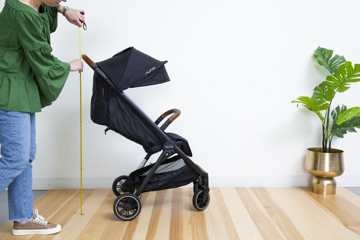 Person measuring the height of Nuna TRVL Stroller on indoor floor
