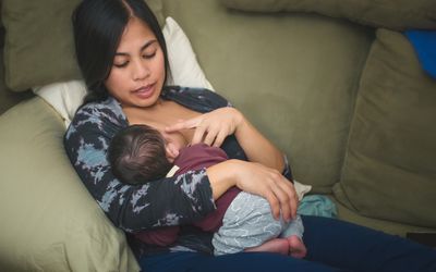 妇女在沙发上给婴儿喂奶