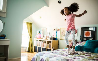 Little girl jumping on bed