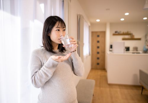 Pregnant woman taking medicine in living room