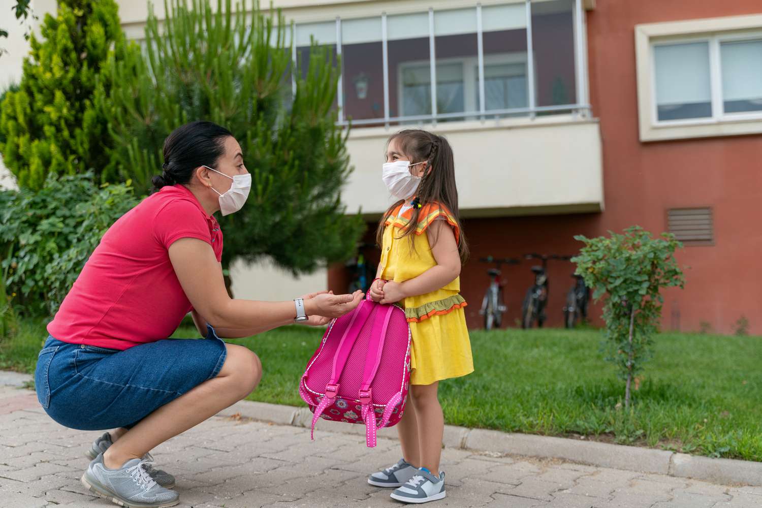 一所学校外，妇女和孩子戴着口罩