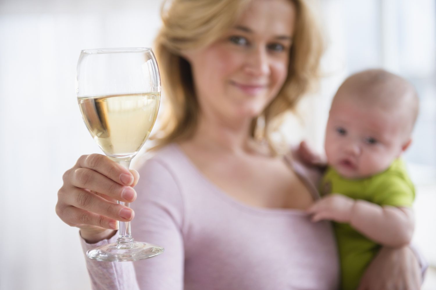 母亲抱着一个婴儿和一杯酒