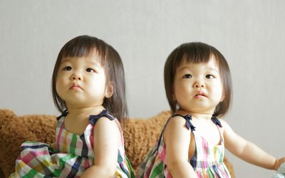 双胞胎女孩穿着一模一样的裙子坐在一起咳嗽