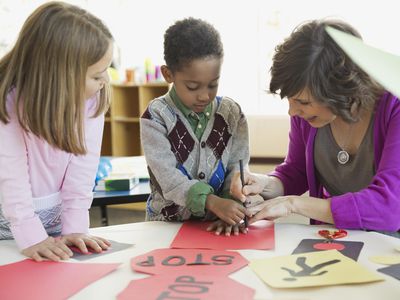 Students with teacher drawing road sign in art class