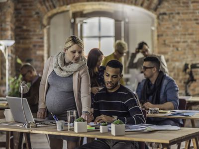 Pregnant woman helping coworker