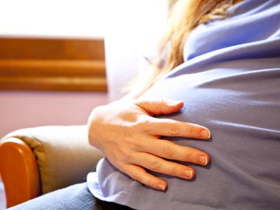 Woman in Blue Holds Her Pregnant Belly