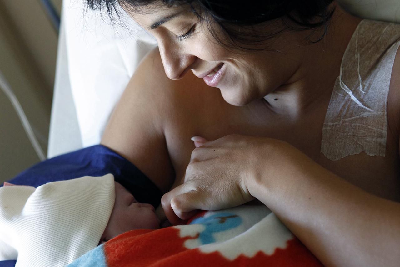 Mother breastfeeding newborn in hospital