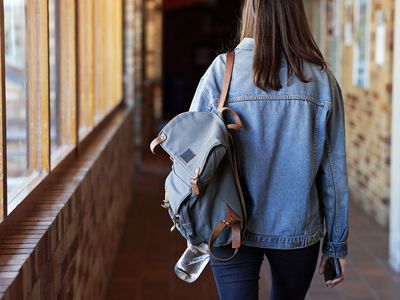 Rear view of young woman with backpack walking in corridor at university