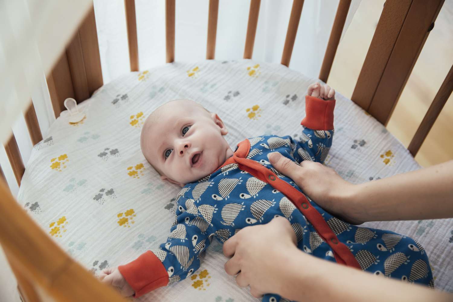 Mother putting her newborn baby boy into bassinet