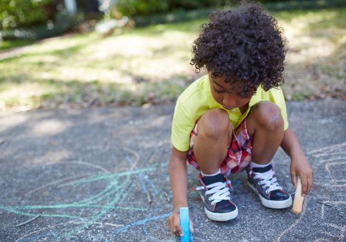 Sidewalk chalk games: boy coloring outside