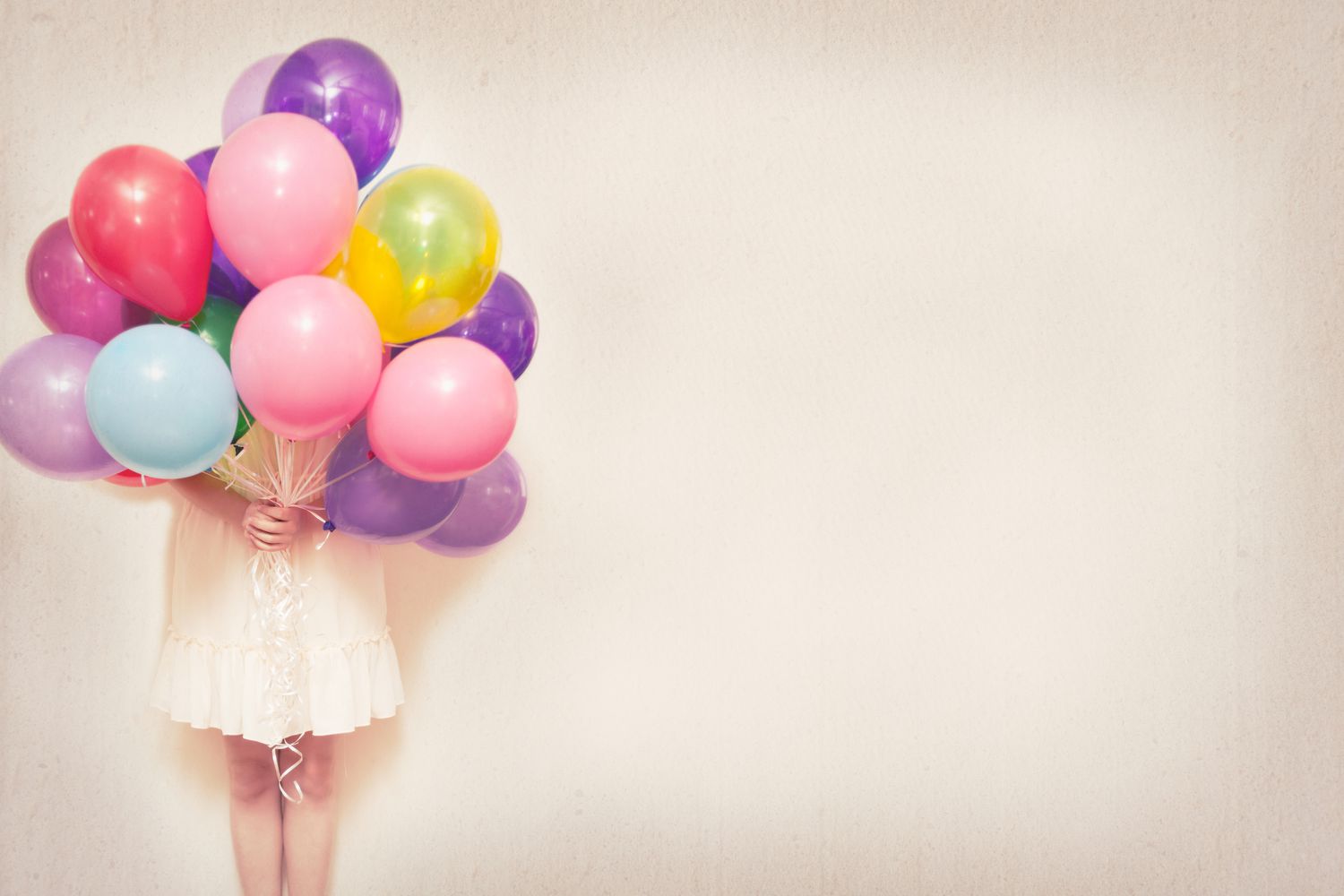 Girl holding a bundle of balloons in front of her face