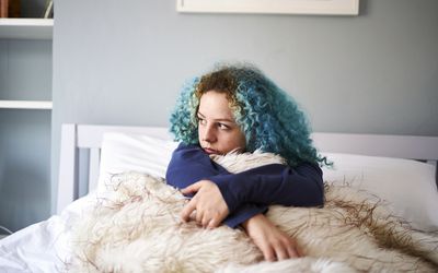 Young woman looking sad and alone in bed