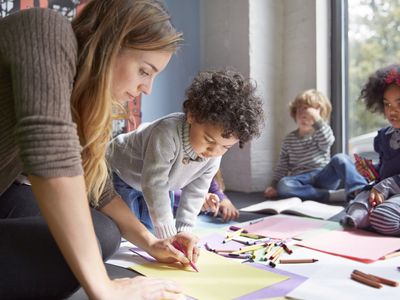 Teacher drawing with students on floor at preschool