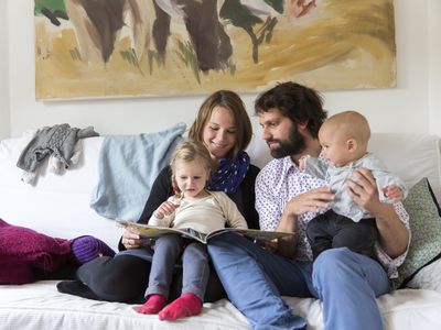 Young family reading storybook together on sofa