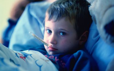 Young boy (3-5) in bed, thermometer in mouth, portrait