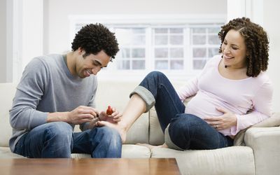 man painting pregnant woman's toes