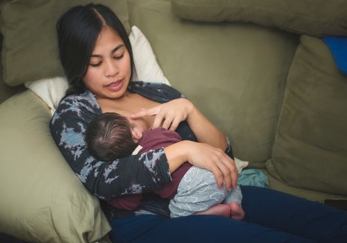 Woman nursing baby on couch