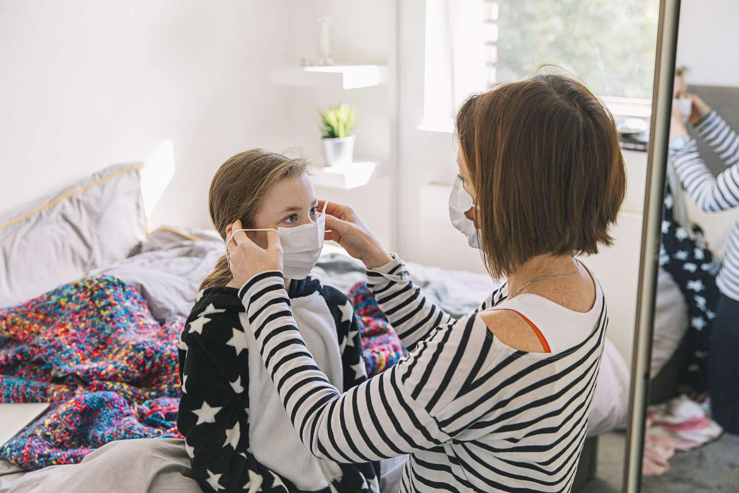 Mother putting face mask on her young daughter